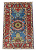 A rectangular hand-woven Persian-style area rug with a central blue field, red borders, and multicolored floral medallions, shown flat against a gray concrete floor.
