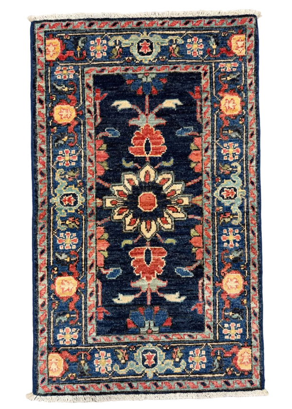 A rectangular traditional area rug with a dark navy blue center and ornate floral motifs in red, beige, and light blue, laid flat on a gray concrete floor.