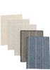 Five rectangular woven fabric swatches arranged in a fan shape on a dark asphalt-like surface. The swatches show different color and texture options: off-white, light beige, dark brown, taupe, and blue-gray.