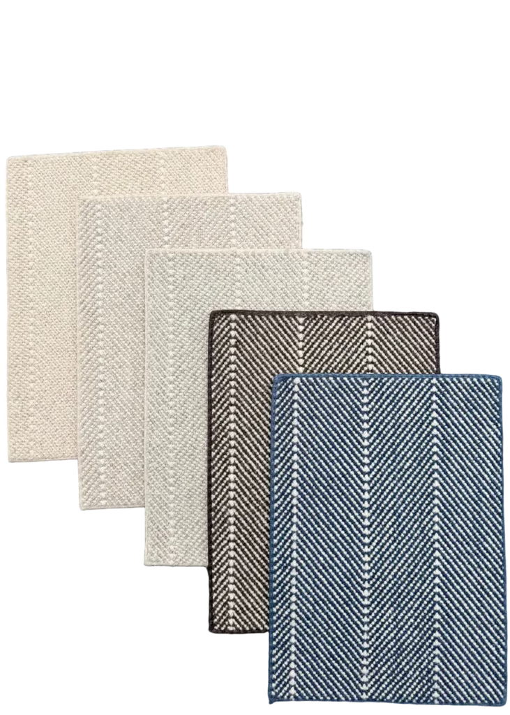 Five rectangular woven fabric swatches arranged in a fan shape on a dark asphalt-like surface. The swatches show different color and texture options: off-white, light beige, dark brown, taupe, and blue-gray.